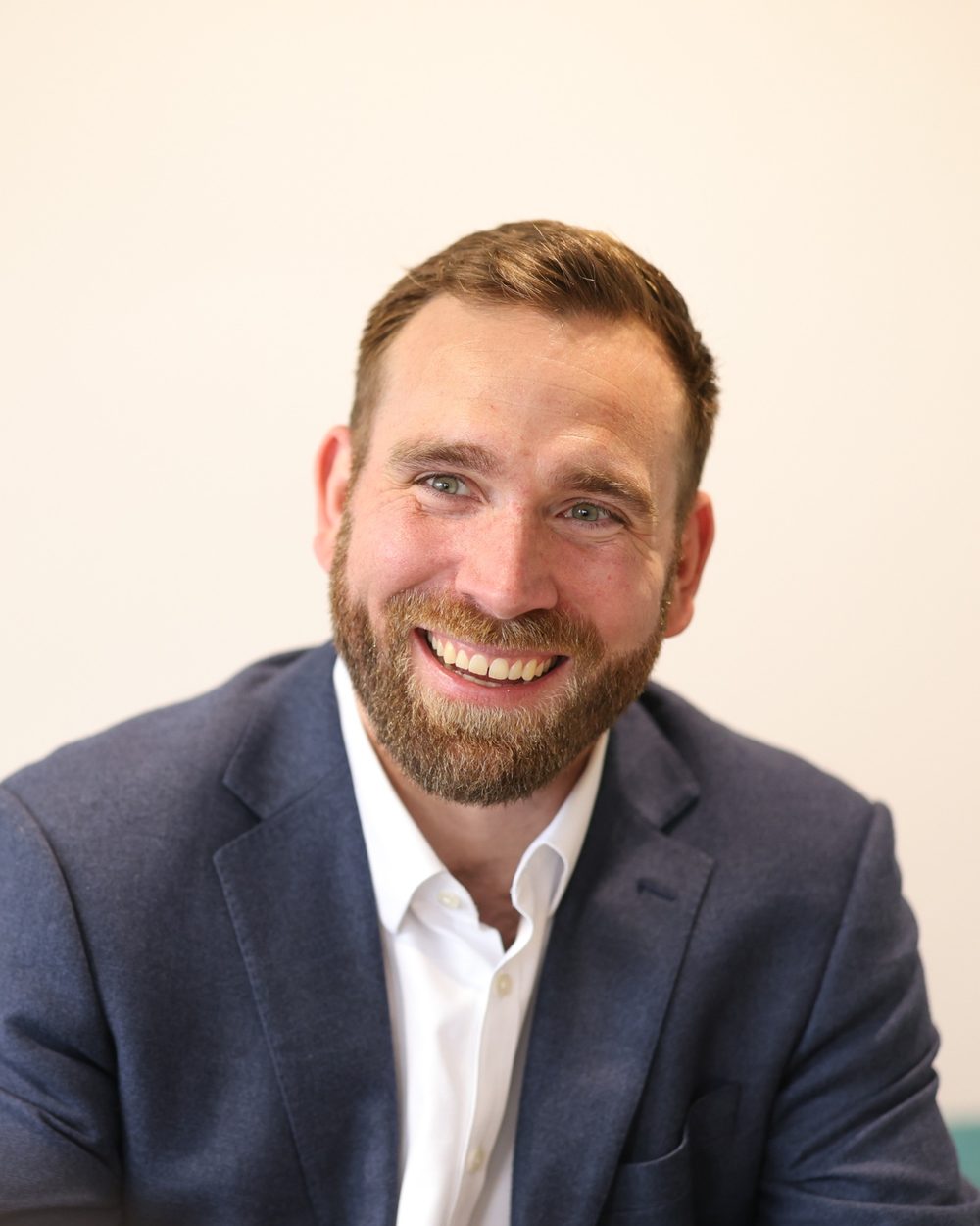 Andrew Marcinko smiling, in a navy blazer and white shirt