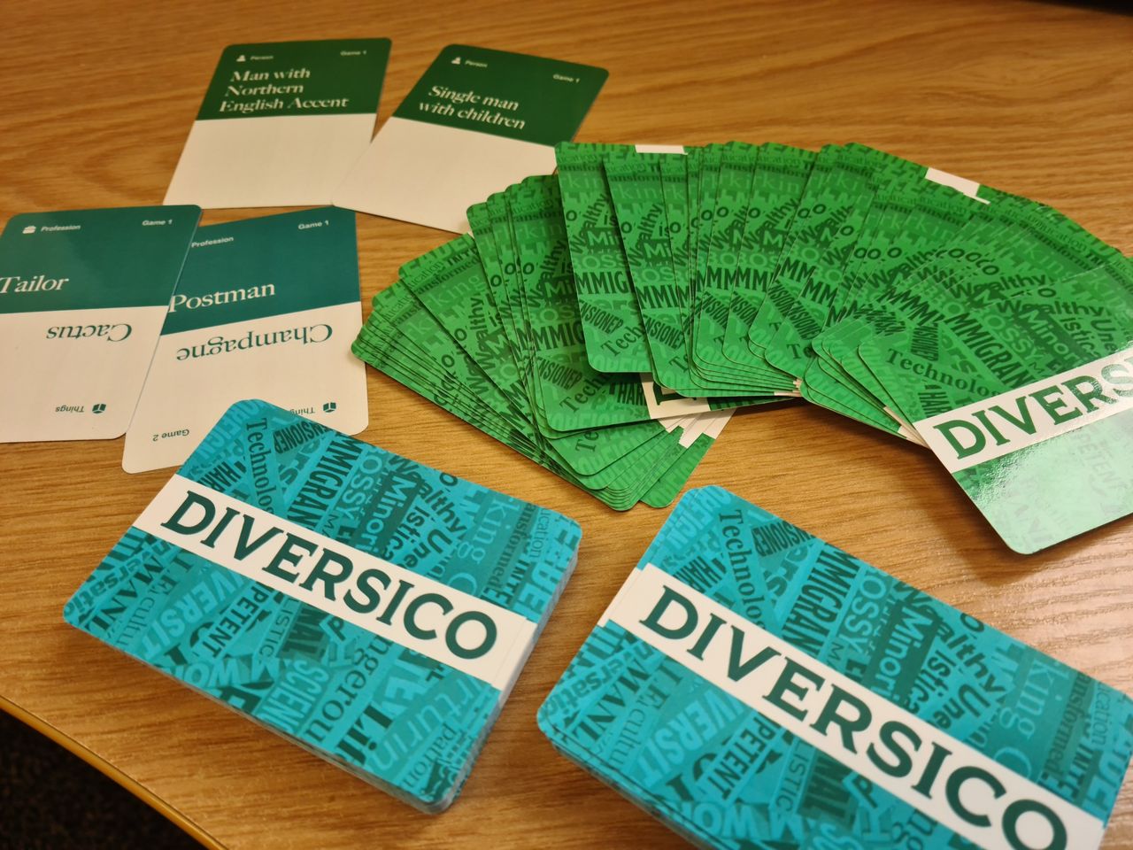 Diversico decks on a table, with example cards including a Person card reading ‘Single man with children’ and a Profession card reading ‘Postman’